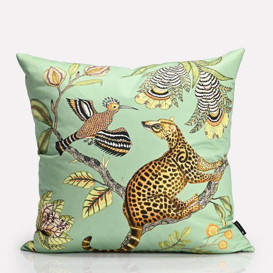 A 50x50cm square cushion cover featuring a soft green background with detailed illustrations of a leopard and exotic birds, surrounded by lush foliage.
