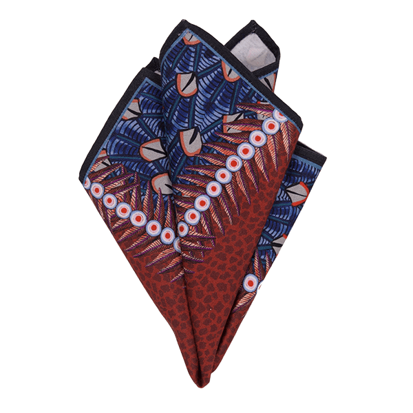 A pair of Ardmore Feather napkins in Royal Red, elegantly folded into a fan shape to showcase the intricate bird wing-inspired pattern with deep red and blue hues.