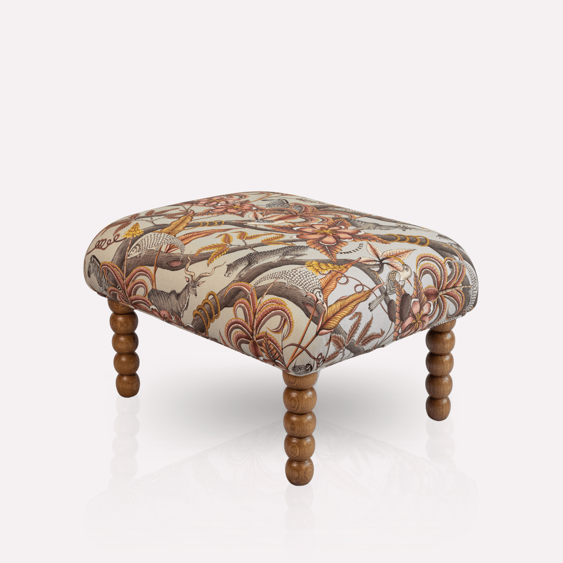 Side view of the Ardmore Kudu Pod Ottoman, showcasing its rich fabric design and finely crafted wooden legs.