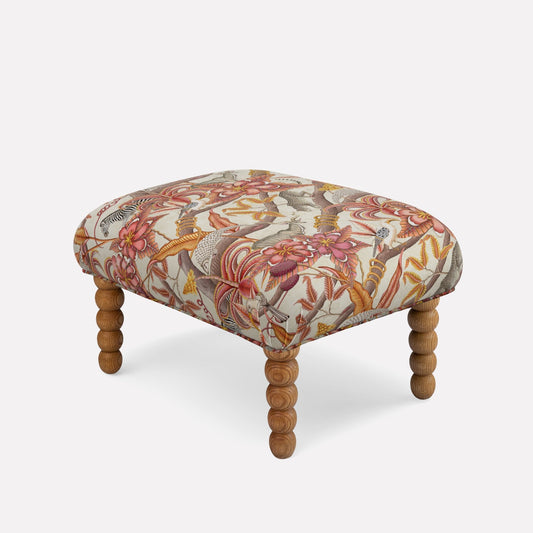 A luxurious ottoman by Ardmore, upholstered in Pangolin Park Plum Velvet, showcasing an exquisite pattern of organic, flowing shapes in warm plum, gold, and earthy tones. 
