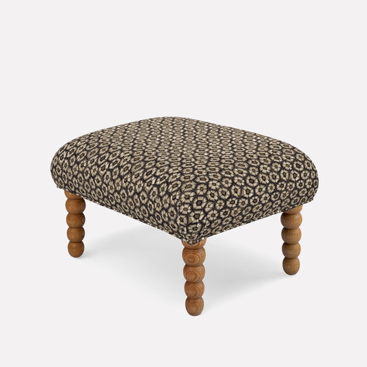 A luxurious ottoman by Ardmore, upholstered in Thanda Tortoise Silver Velvet, featuring an intricate tortoise-shell pattern set against an elegant silver-toned fabric. The sumptuous blend of 66% cotton, 31% viscose, and 3% polyester ensures both comfort and durability. Supported by sturdy, sculpted wooden legs, this ottoman embodies sophisticated elegance and artistic expression, making it a stunning statement piece for any refined interior.