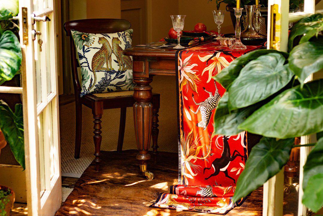 Decorative setup featuring the Lovebird Leopards Tanzanite Cushion Cover styled with complementary vibrant patterns in a cosy room setting.