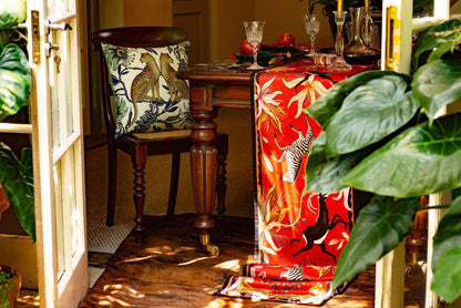 Decorative setup featuring the Lovebird Leopards Tanzanite Cushion Cover styled with complementary vibrant patterns in a cosy room setting.