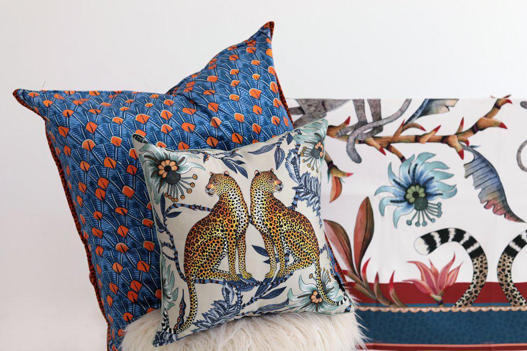 Close-up of the Lovebird Leopards Tanzanite cushion cover and other decor items arranged in a living room, enhancing the overall aesthetic with detailed prints.