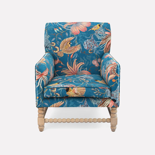 A luxurious Lucky Bean Chair by Ardmore, upholstered in Thanda Nest Midnight Velvet. The fabric showcases an intricate botanical and wildlife-inspired pattern, featuring lush foliage and exotic animals in rich, vibrant tones.