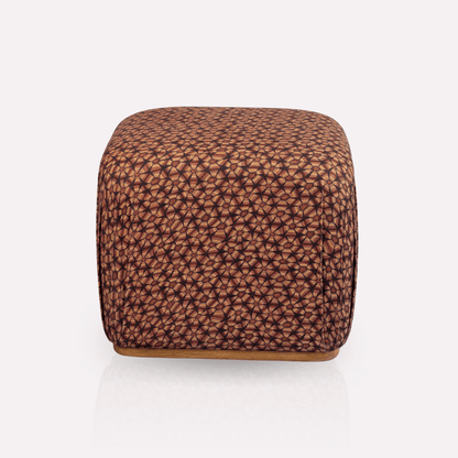 A luxurious Nyala Ottoman with a rich tortoise shell-inspired pattern in deep plum and earthy brown tones. The ottoman has a smooth, cube-like silhouette, offering a plush and sophisticated seating or decorative piece.