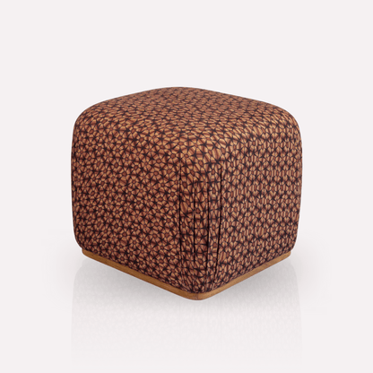 A different angle of the Nyala Ottoman, showcasing its soft, rounded edges and intricate woven fabric texture. The deep hues and geometric tortoise-shell motif add a touch of African elegance and warmth to the design.