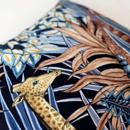 Close-up of the Sabie Forest Dawn cushion cover, focusing on the delicate depiction of a giraffe amid detailed leaves and flowers in blue and beige tones.