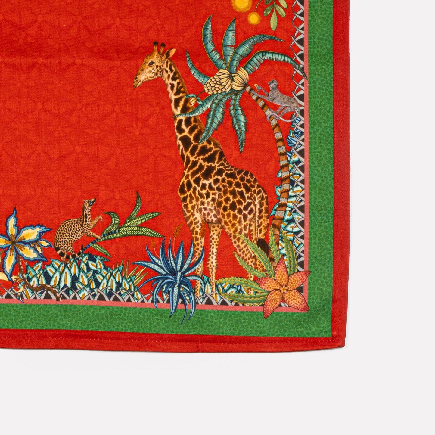 A zoomed-in section of the Ardmore Sabie Forest Napkin in Royal Red, showcasing a majestic leopard among lush foliage, with a giraffe subtly blending into the background.