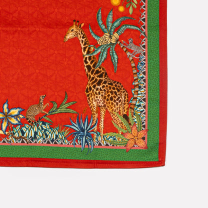 A zoomed-in section of the Ardmore Sabie Forest Napkin in Royal Red, showcasing a majestic leopard among lush foliage, with a giraffe subtly blending into the background.