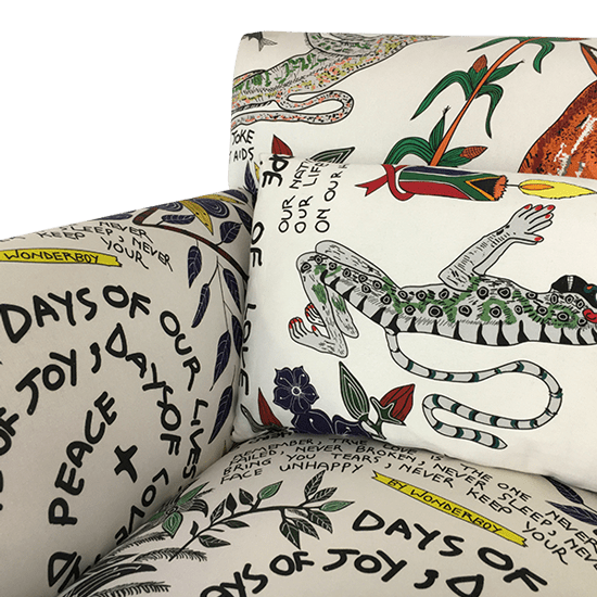 A close-up shot of the backrest and cushion, displaying elements of the hand-drawn illustrations, including African wildlife, figures, and script-style text woven into the design.