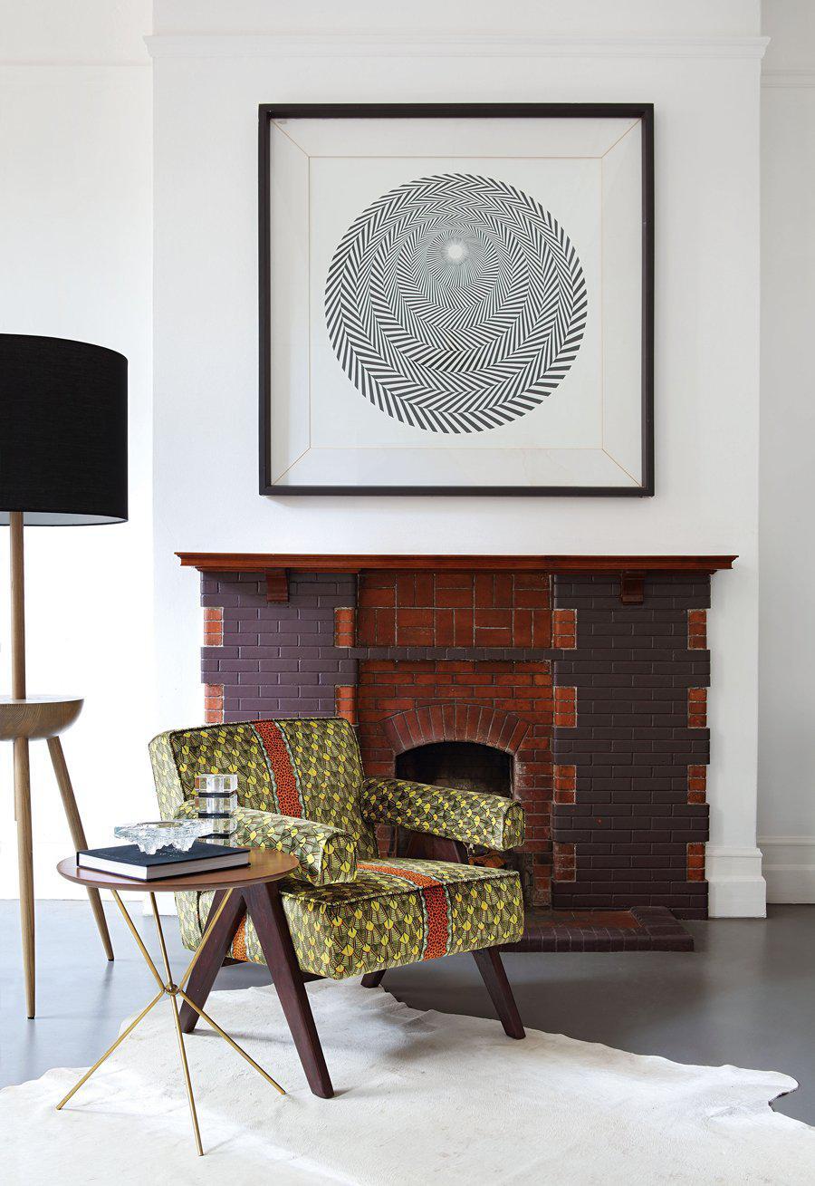 The chair placed in an elegantly decorated living space, positioned near a contemporary fireplace with a framed artwork on the wall.