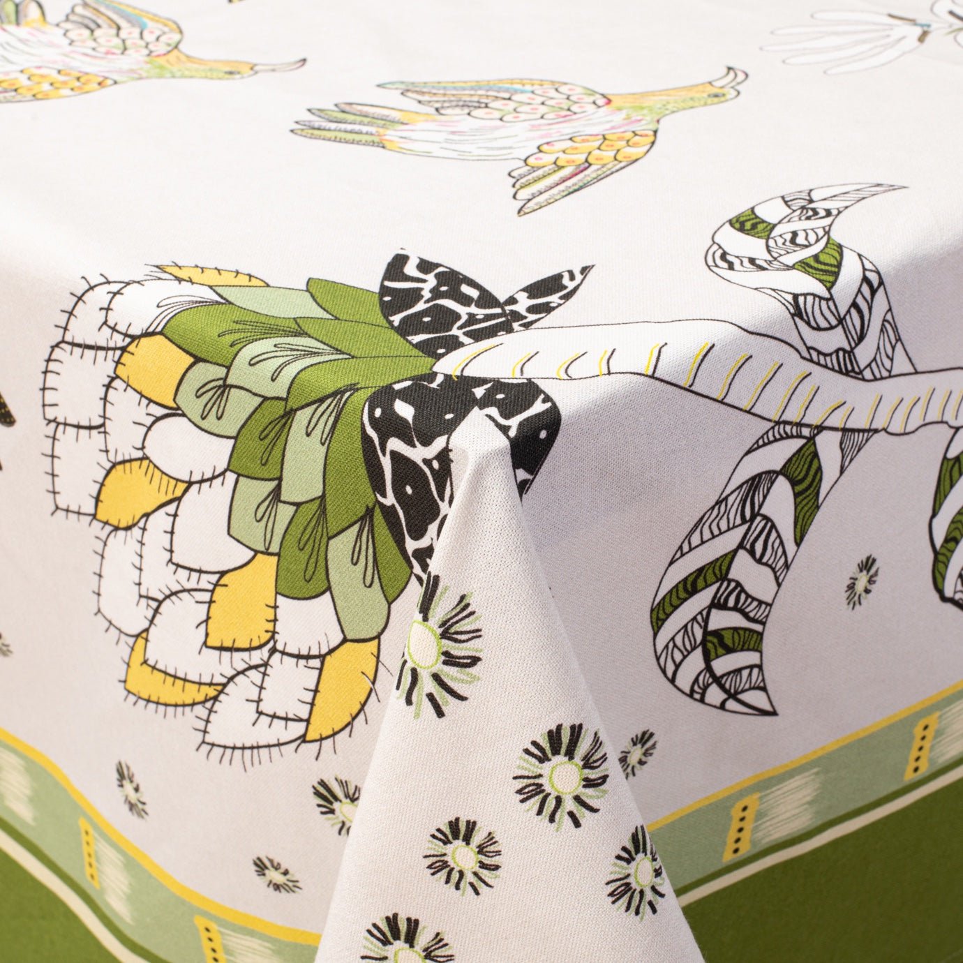 The Bird Fynbos Tablecloth in Savannah draped over a table, showcasing its intricate floral and bird motifs.