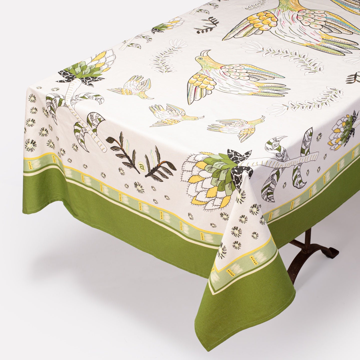 A full view of the Bird Fynbos Tablecloth in Savannah, elegantly draped over a dining table, featuring a delicate bird and botanical print with a green border.