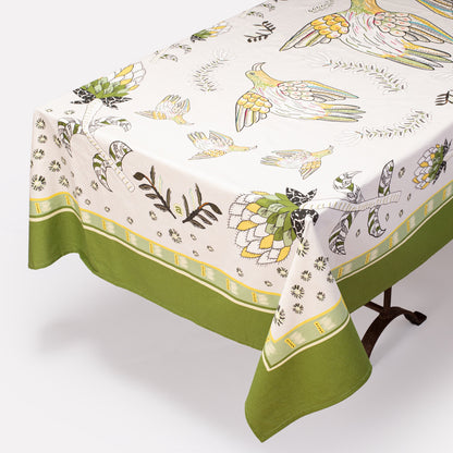 A full view of the Bird Fynbos Tablecloth in Savannah, elegantly draped over a dining table, featuring a delicate bird and botanical print with a green border.