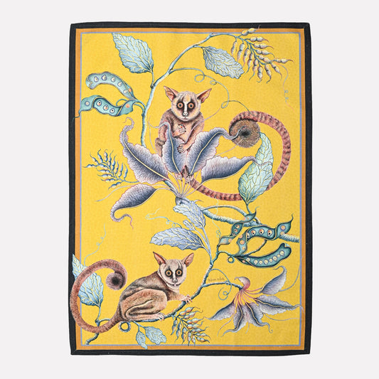 A vibrant tea towel featuring an artistic depiction of playful bush babies perched among botanical elements, set against a rich golden-yellow background.