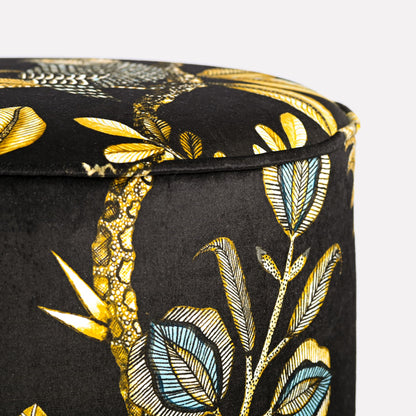 Side close-up of the Ardmore Camp Critter Brass Velvet Pouffe, highlighting the luxurious texture of the fabric and the detailed golden embroidery of African-inspired wildlife patterns.