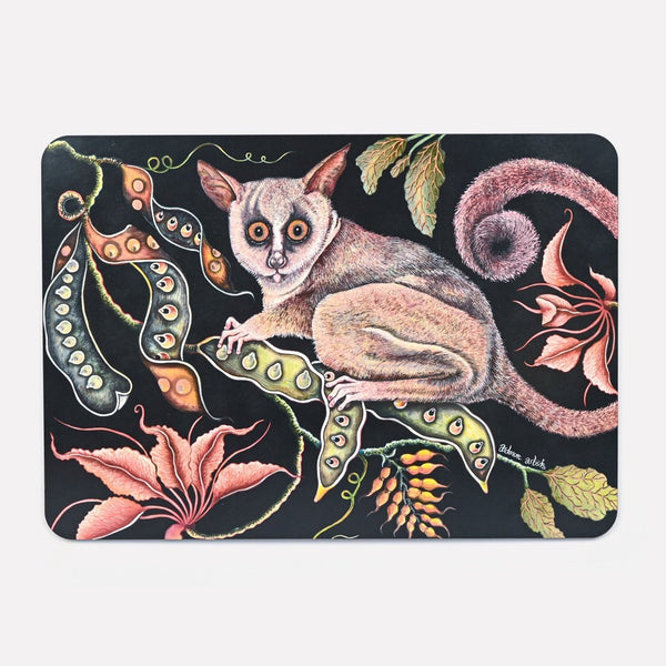 A hardboard placemat featuring a detailed illustration of a bush baby with large, glowing eyes, surrounded by lush foliage and exotic flowers against a dark background.