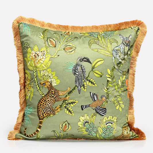 A 60x60cm cushion cover featuring a plush velvet fabric with an intricate wildlife-inspired print of leopards, birds, and lush greenery, framed with an elegant fringe trim.