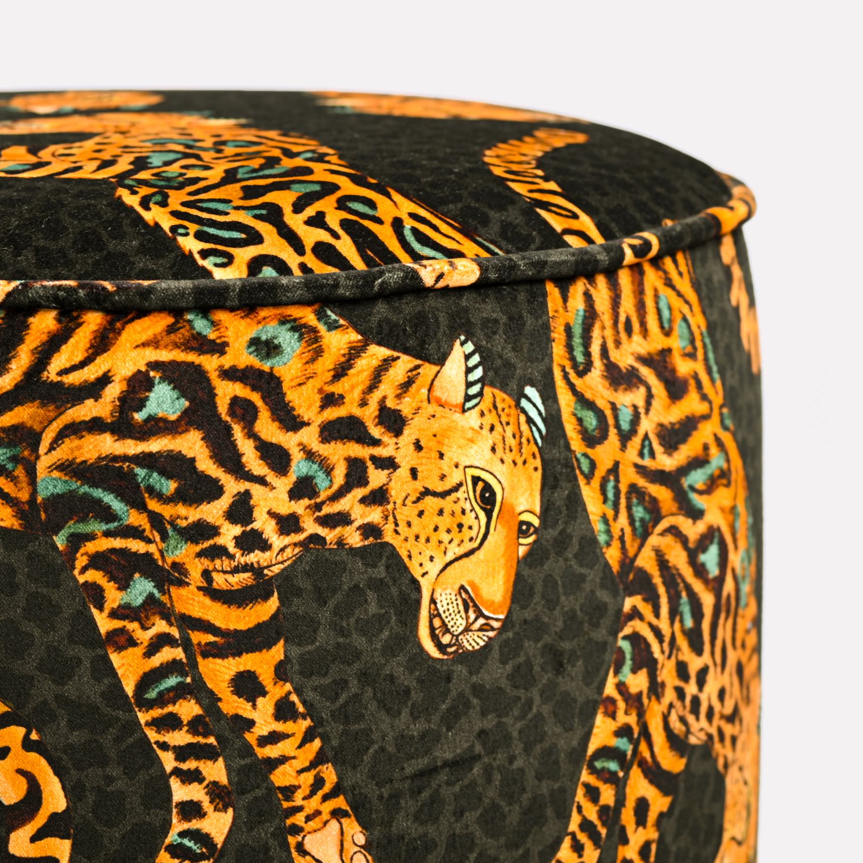 Close-up of the Ardmore Cheetah Kings Amber Velvet Pouffe, showcasing the detailed cheetah patterns embroidered into the plush black velvet fabric.