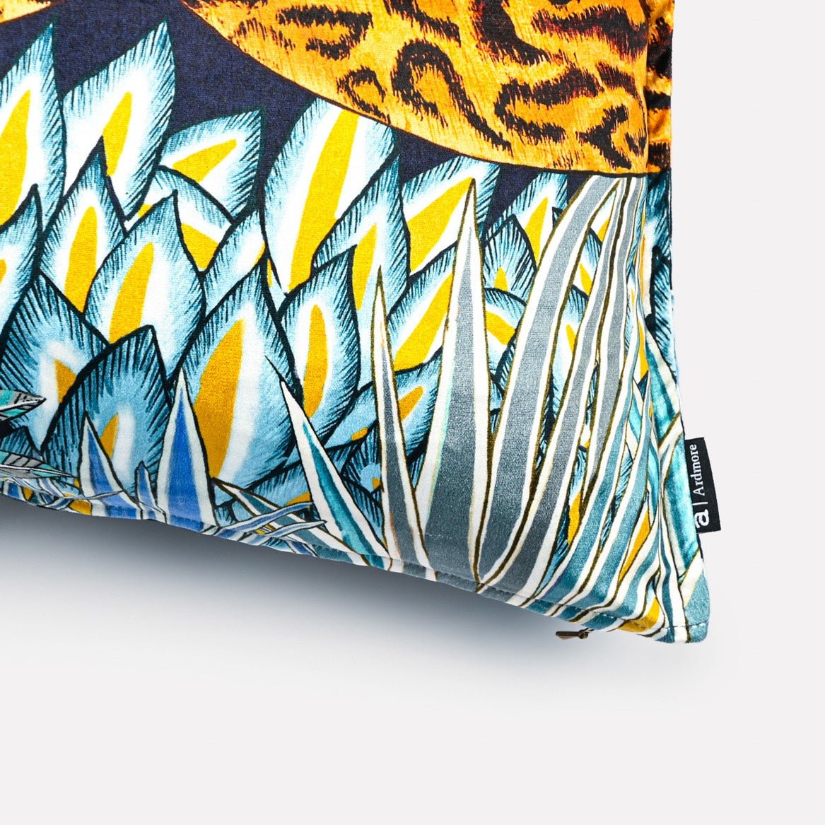 Close-up of the Cheetah Kings Forest Tanzanite velvet cushion, highlighting detailed tropical foliage and geometric designs in bold blue and gold shades.