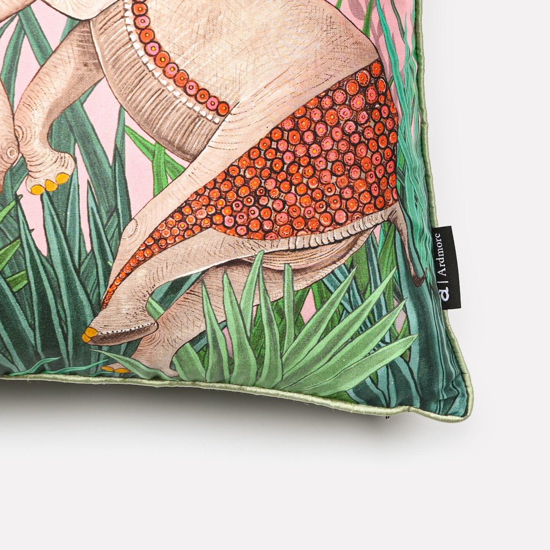 Angled close-up of the Dancing Elephant Magnolia Silk cushion cover, highlighting the fine details of the elephants and the delicate magnolia blossom accents on the luxurious silk fabric.