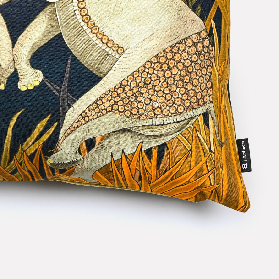 Angled close-up of the Dancing Elephant Moonlight cotton cushion cover, highlighting the fine details of the elephants and the vibrant golden grass accents on the navy cotton fabric.