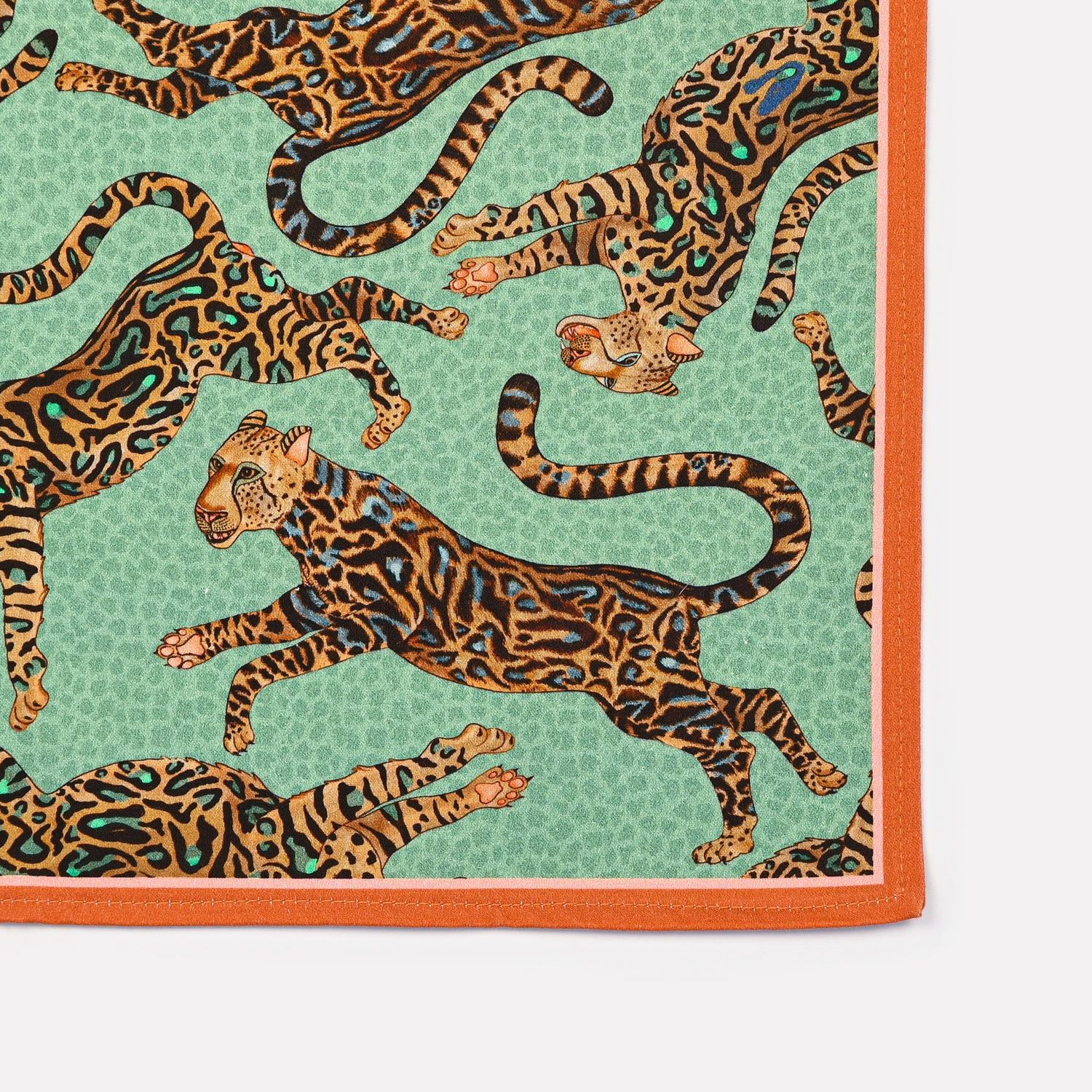 A stack of Ardmore Cheetah King napkins in Jade, arranged to display their bold border design and artistic craftsmanship.