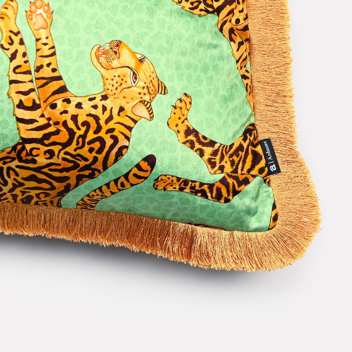 Angled view of the Cheetah Kings Jade velvet cushion cover with fringe, showcasing the intricate cheetah patterns and the opulent fringe detail.
