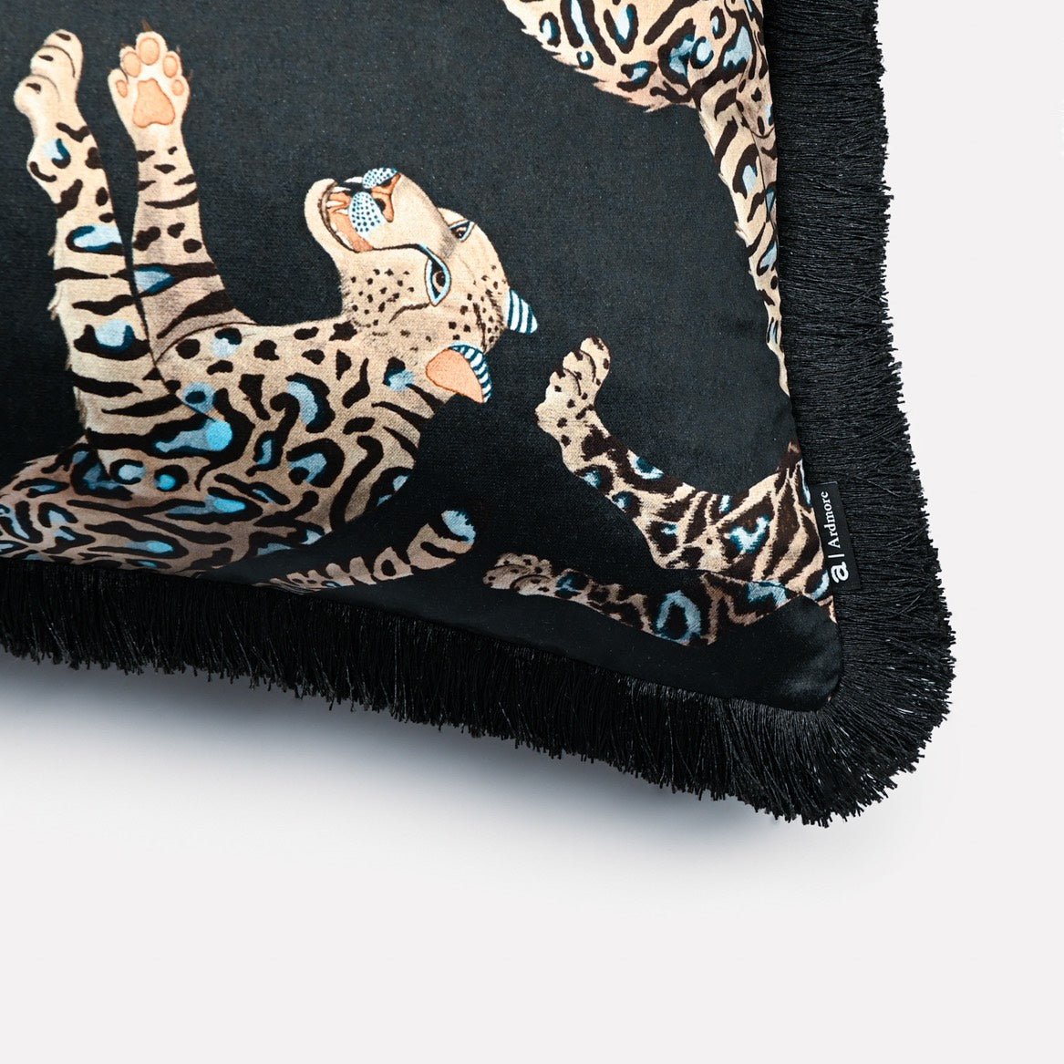 Close-up of the Cheetah Kings Starry Nights velvet cushion cover, showcasing the detailed cheetah patterns and the elegant black fringe edging.