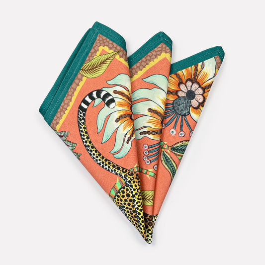 A pair of Ardmore Leopard Napkins in Coral, folded into a fan shape, displaying the vibrant floral and leopard design with rich coral and teal accents.