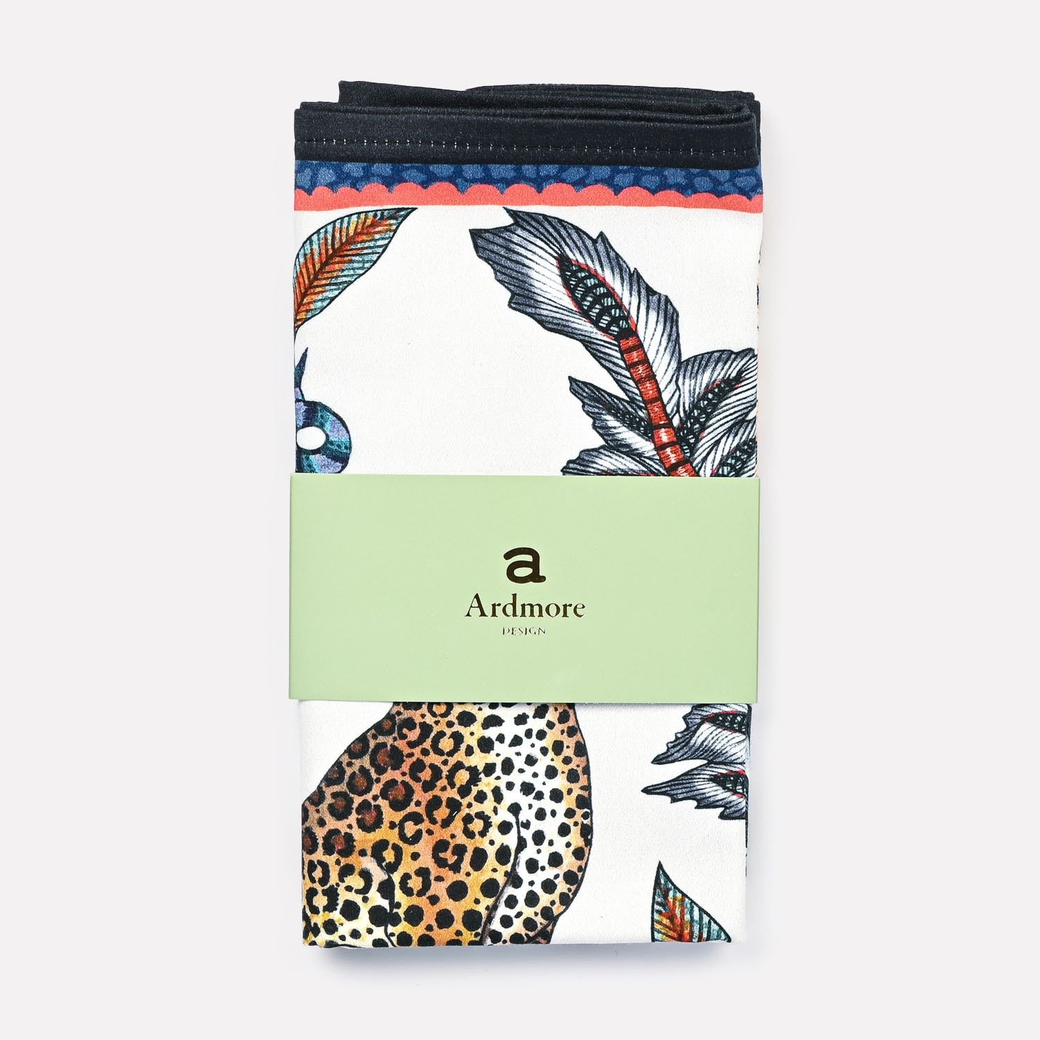 A neatly folded Ardmore Leopard Napkin in Frost, wrapped in its original branded packaging, presenting the fine craftsmanship and intricate detailing.