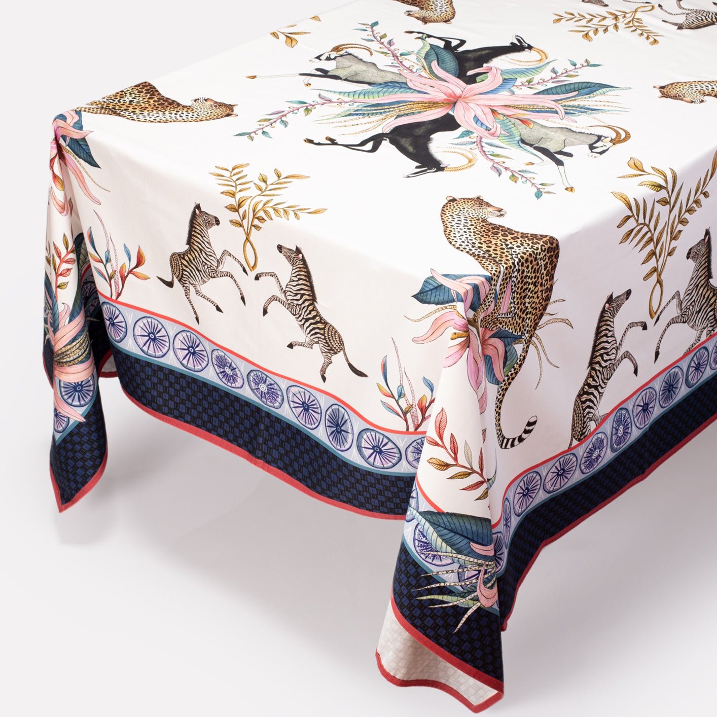 A full-table view showcasing the elegant drape of the tablecloth, revealing detailed patterns of zebras, leopards, and botanical elements.