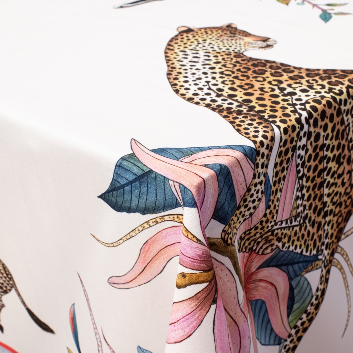 A close-up view of the tablecloth’s design, focusing on a majestic leopard resting among vivid florals and golden foliage.