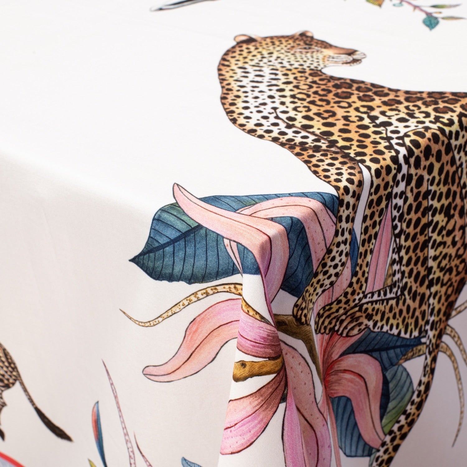 A close-up view of the tablecloth’s design, focusing on a majestic leopard resting among vivid florals and golden foliage.