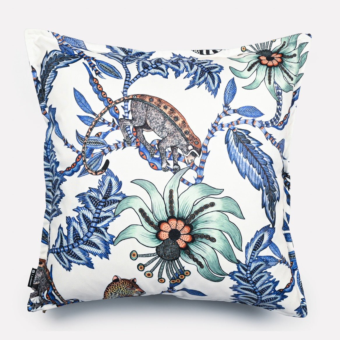 Front view of the Monkey Bean Tanzanite cushion cover, showcasing a harmonious design of tropical foliage and wildlife in vibrant blue and green tones on a white base.