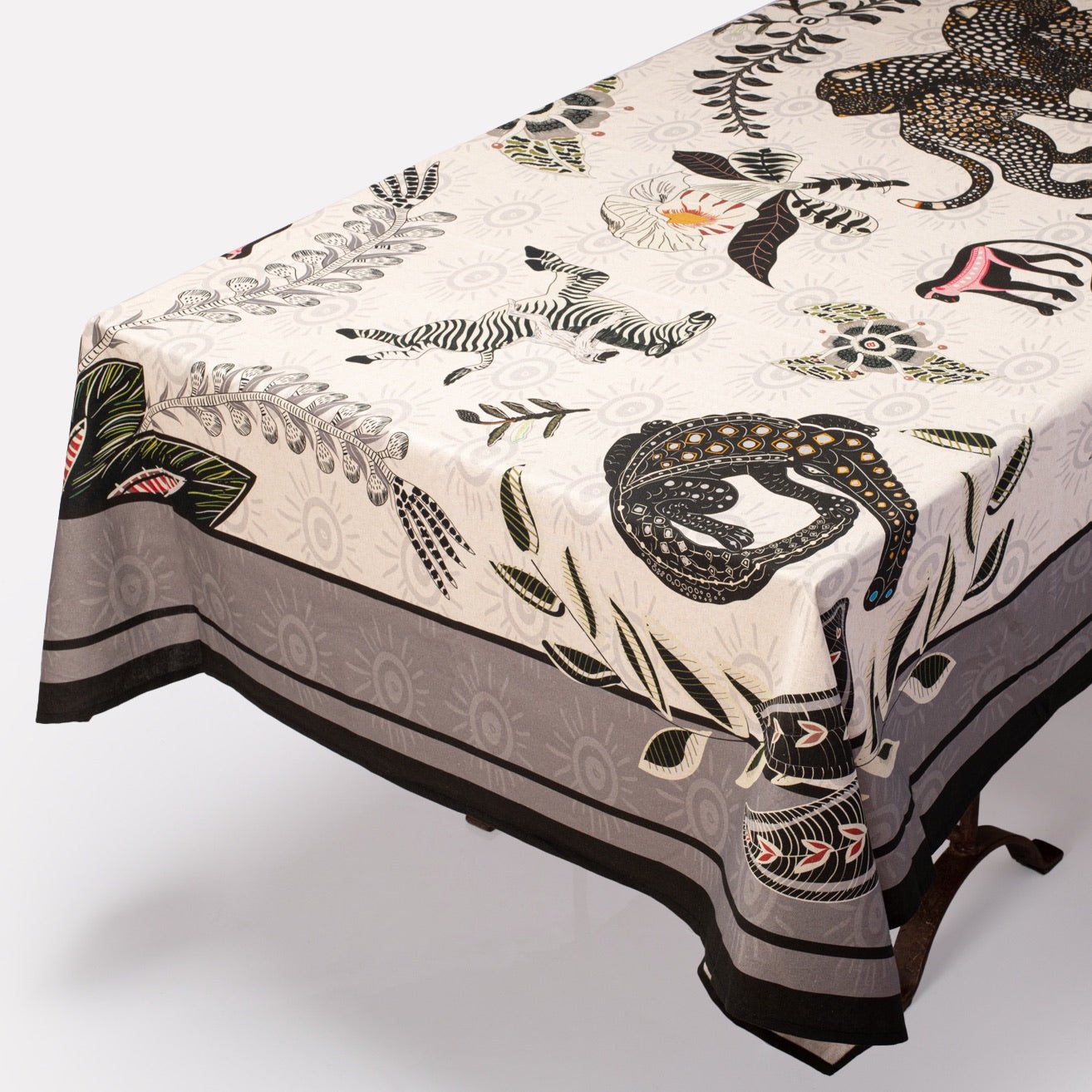 The Royal Leopard Tablecloth in Charcoal on Natural Linen elegantly draped over a table, showcasing its luxurious fabric and intricate animal patterns.