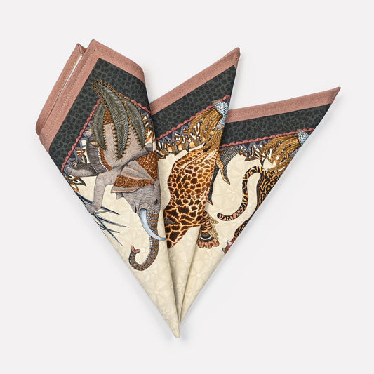 A pair of Ardmore Sabie Forest Napkins in Stone, folded into a fan shape, highlighting the intricate wildlife and foliage-inspired design on a neutral stone background.
