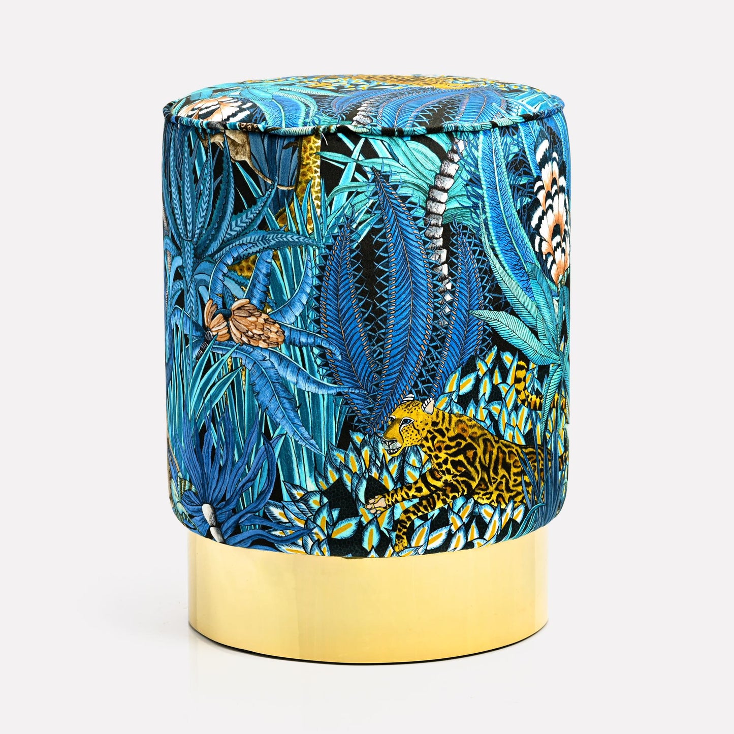 Luxurious velvet pouffe featuring Ardmore's Sabie Forest Tanzanite design, showcasing a vivid blue jungle-inspired pattern with golden accents, set atop an elegant brass base.