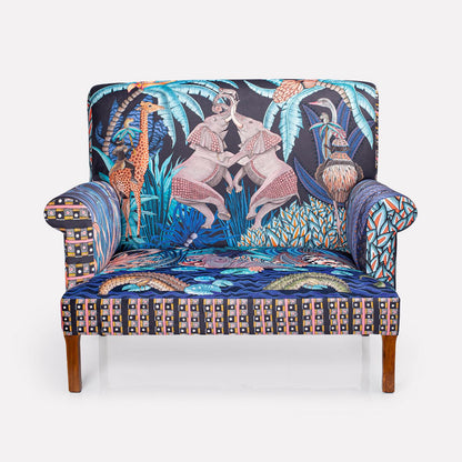 A full-frontal view of the Ardmore Sabie Sofa in Tanzanite, showcasing its intricate design featuring elephants, a juggling monkey, and vibrant flora.