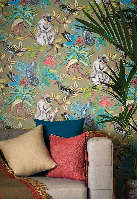 A cosy living room featuring a sofa with colourful cushions set against a bold green Ardmore Savuti wallpaper, adorned with intricate wildlife motifs.