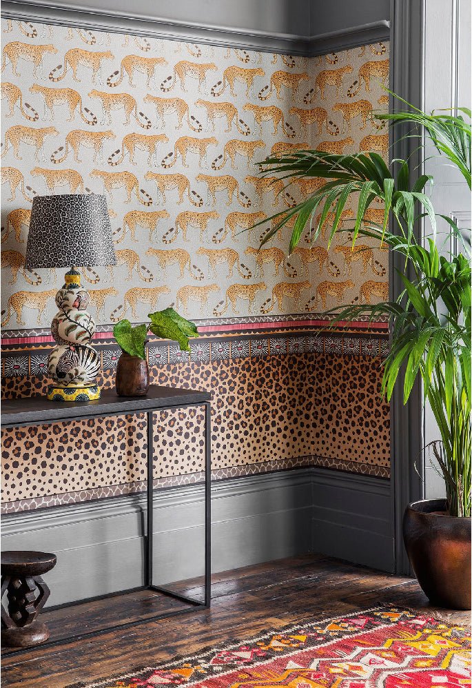 A sophisticated room showcasing the Zulu Border wallpaper, blending warm tones with a refined leopard spot design.