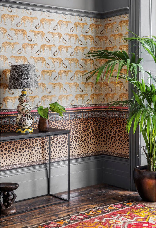 A sophisticated room showcasing the Zulu Border wallpaper, blending warm tones with a refined leopard spot design.